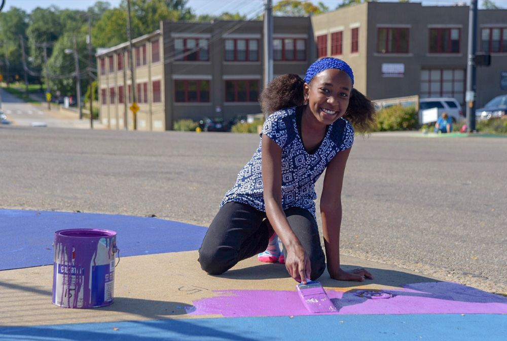 Young girl painting a mural in Akron